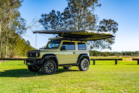 small rooftop tent attached to car sitting in grass field